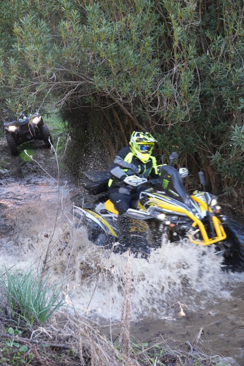 Quad giallo che spruzza acqua nel guado del rio